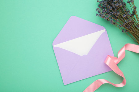 Mockup with envelopes, lavender and ribbon on mint background. Top view.