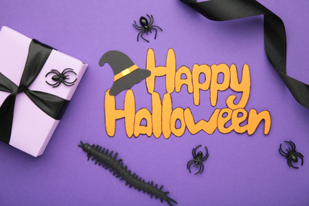 Happy Halloween holiday concept. Flat lay gift boxes, orange pumpkins, bats, spiders on violet background. Halloween greeting card template. Top viewの写真素材