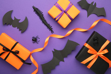 Happy Halloween holiday concept. Flat lay gift boxes, orange pumpkins, bats, spiders on violet background. Halloween greeting card template. Top viewの写真素材