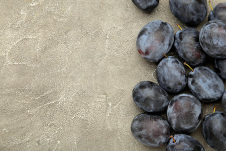 Ripe plumes on gray concrete background. The autumn harvest. Top view