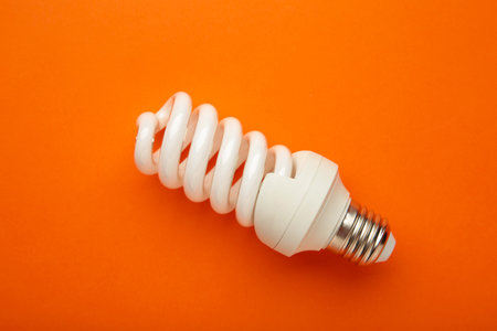 Light bulb on orange background. Space for text. Top view