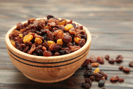 Dry raisins in wooden bowl on brown wooden background. Top viewの写真素材