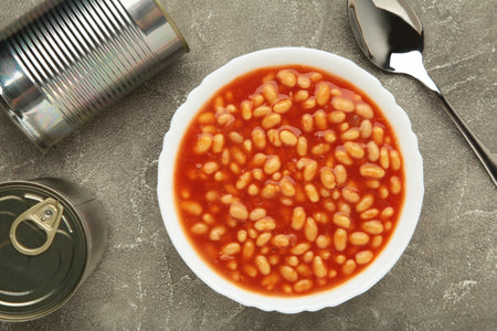 Baked beans in tomato sauce in a white ceramic bowl on gray background. Top viewの写真素材
