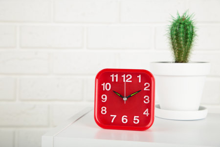 Good morning concept - modern alarm clock and houseplant on bedside table. Top view