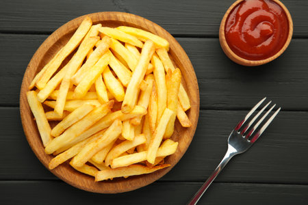 French fries on wooden plate with ketchup in bowl on black wooden background. Top viewの写真素材