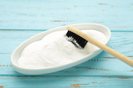 Toothbrush and baking soda to clean on blue background. Top view
