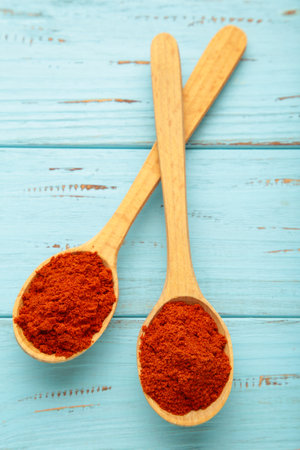 Powder paprika with wooden spoon on blue wooden background. Top viewの写真素材