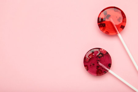 Red sweet lollipops with berries on pink background. Space for text. top viewの写真素材