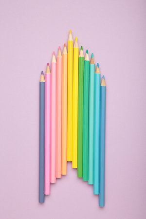 Pastel color pencils on purple background. Vertical photo. Top view