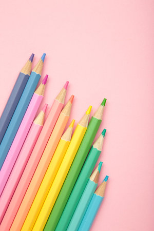 Pastel color pencils on pink background. Vertical photo. Top viewの写真素材