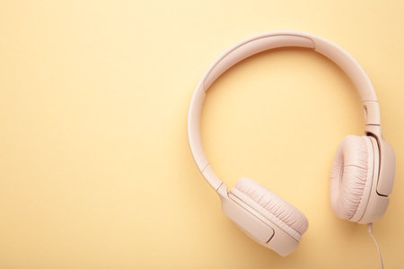 Pink headphones on beige background. Top view