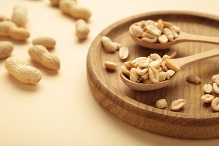 Fresh healthy peanuts in bowl and spoon on beige background. Top view. Super foods.