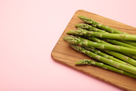 Fresh green asparagus on cutting board on pink background. Healthy food concept.の写真素材
