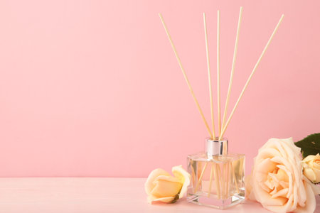 Aromatic reed air freshener and rose on pink background. Space for text. Top view