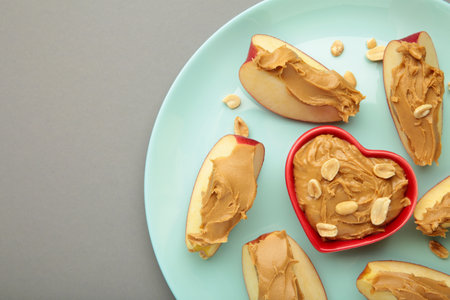 Slices of fresh apple with peanut butter in bowl on mint plate. Top viewの写真素材