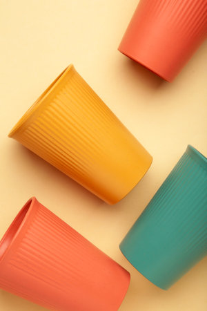 Eco plastic glass of various colors on beige background. Top view