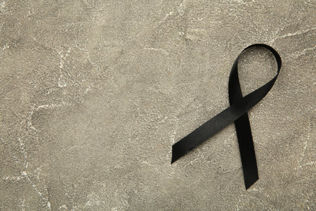 Black awareness ribbon on gray concrete background. Top viewの写真素材