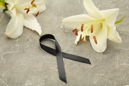 White liles flowers with black ribbon. Mourning or funeral backgroundの写真素材