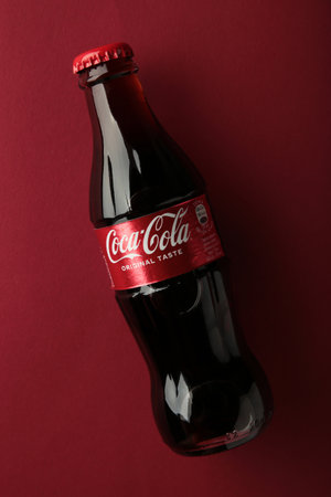 Mykolaiv, UKRAINE - July, 2024: Coca-Cola Classic in a glass bottle on red background. Top view
