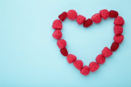 Red chewing sweets in the form of berries. Sweets in the form of raspberries on blue background.の写真素材