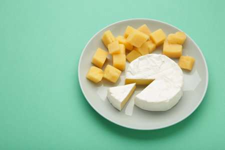 Parmesan cheese with camembert on plate on mint background. Top viewの写真素材