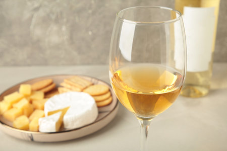 Wine tasting. Parmesan cheese with glass of wine on light background. Cheese plate. Top view