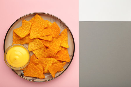 Nachos on plate with ketchup and cheese sauce on colorful background. Mexican dishの写真素材