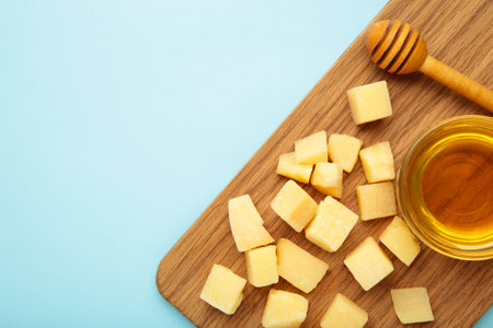 A piece of Parmesan cheese with honey on cutting board on blue background. Top viewの写真素材