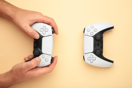 Mykolaiv, UKRAINE - July, 2024: Female hand holding a new Sony Playstation 5 controller on beige