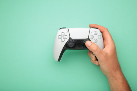 Mykolaiv, UKRAINE - July, 2024: Female hand holding a new Sony Playstation on mint background.