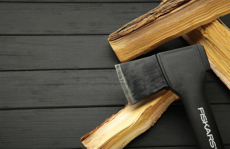 Mykolaiv, UKRAINE - July, 2024: Ax Fiskars with wood on black backgroundのeditorial素材