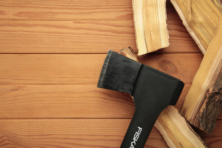 Mykolaiv, UKRAINE - July, 2024: Ax Fiskars with wood on brown background