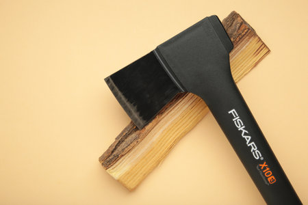 Mykolaiv, UKRAINE - July, 2024: Ax Fiskars with wood on beige backgroundのeditorial素材