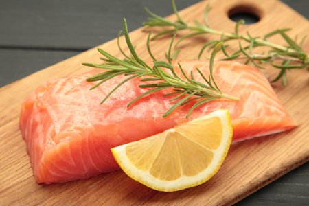 Red fish. Raw salmon fillet with rosemary and lemon on cutting board. Top view