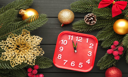Retro alarm clock, fir branches with cones on black wooden background. Top viewの写真素材