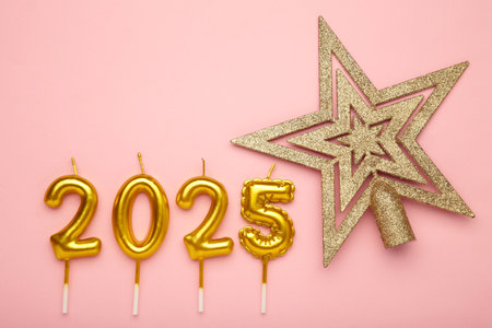 Holiday background Happy New Year 2025. Numbers of year 2025 made by gold candles with Christmas star on pink background.の写真素材