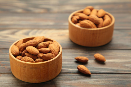 Fresh natural healthy almonds nuts in two wooden bowls on brown wooden background. Topの写真素材