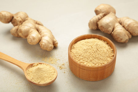 Ginger powder on bowl with fresh ginger root on light background.の写真素材