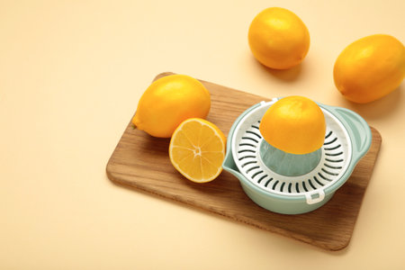 Squeezer and lemons on cutting board on beige background. Top viewの写真素材