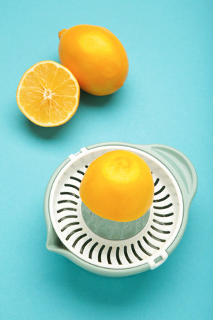 Squeezer and lemons on blue background. Vertical photo. Top view