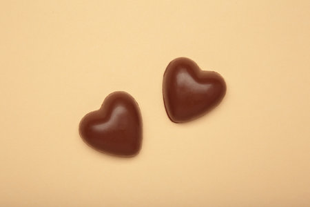 Red chocolate sweets as heart on beige background. Valentine's day concept. Top viewの写真素材