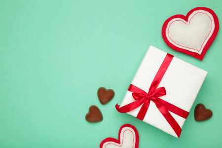 Valentine's day greeting card with gift, hearts chocolate sweets on mint background. Top viewの写真素材