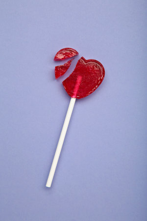 Broken heart lollipop on purple background. Top viewの写真素材