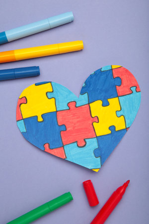 World Autism Awareness day, mental health care concept with puzzle on heart on purple background.
