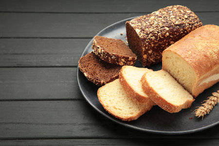 Different bread on plate on black wooden background. Top viewの写真素材