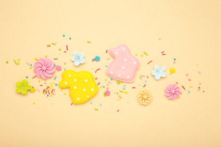 Tasty Easter cookies in shape on bunny and candies on beige background. Top view