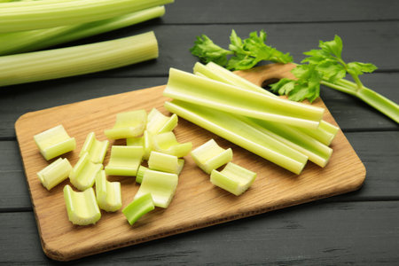 Fresh green cut celery on cutting board on black wooden background. Top viewの写真素材