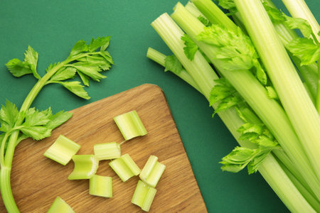 Fresh green cut celery on cutting board on green background. Top viewの写真素材