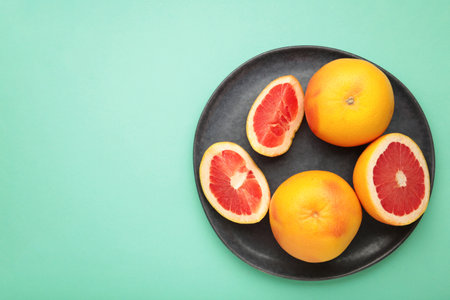 Fresh Organic grapefruit on dark plate on mint background, top view. Space for textの写真素材