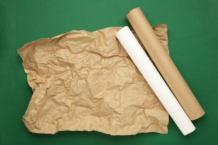 Rolls of white and brown paper on green background. Top view